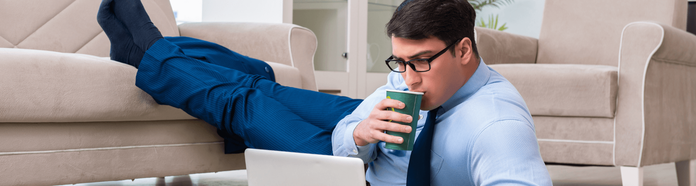 Homme en télétravail les pieds sur le canapé, il boit son café